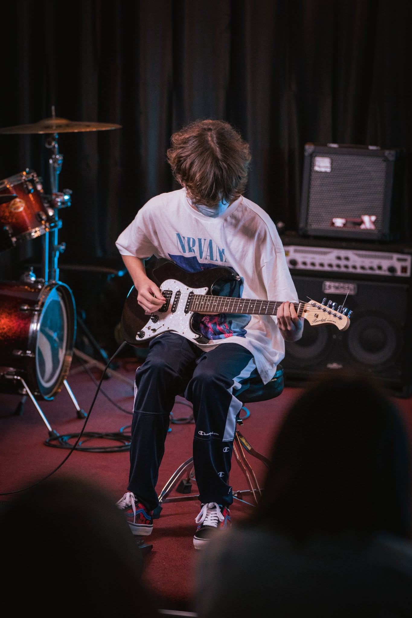 Person playing electric guitar on stage.