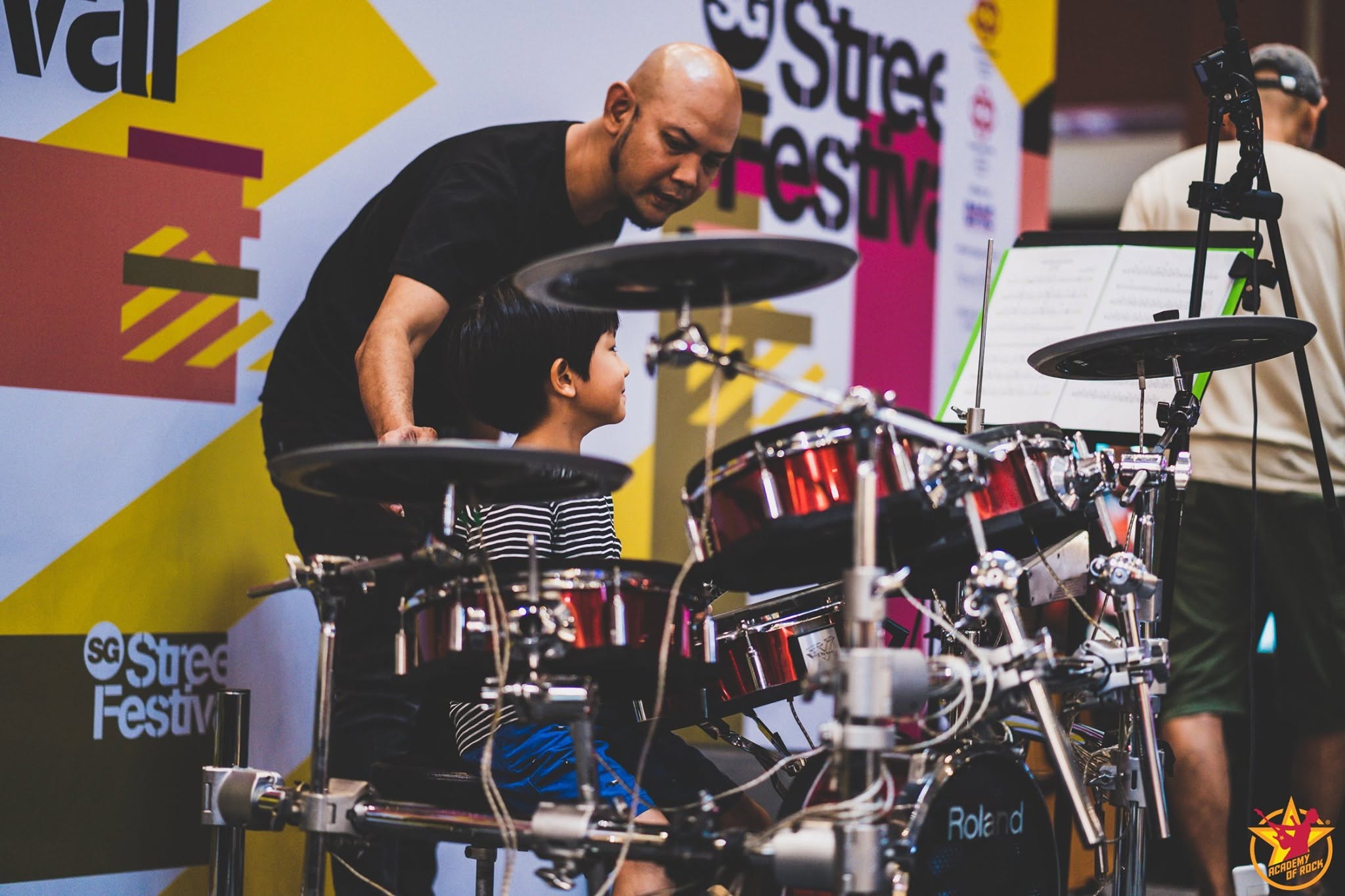 Academy of Rock teacher guiding a young drummer during a performance
